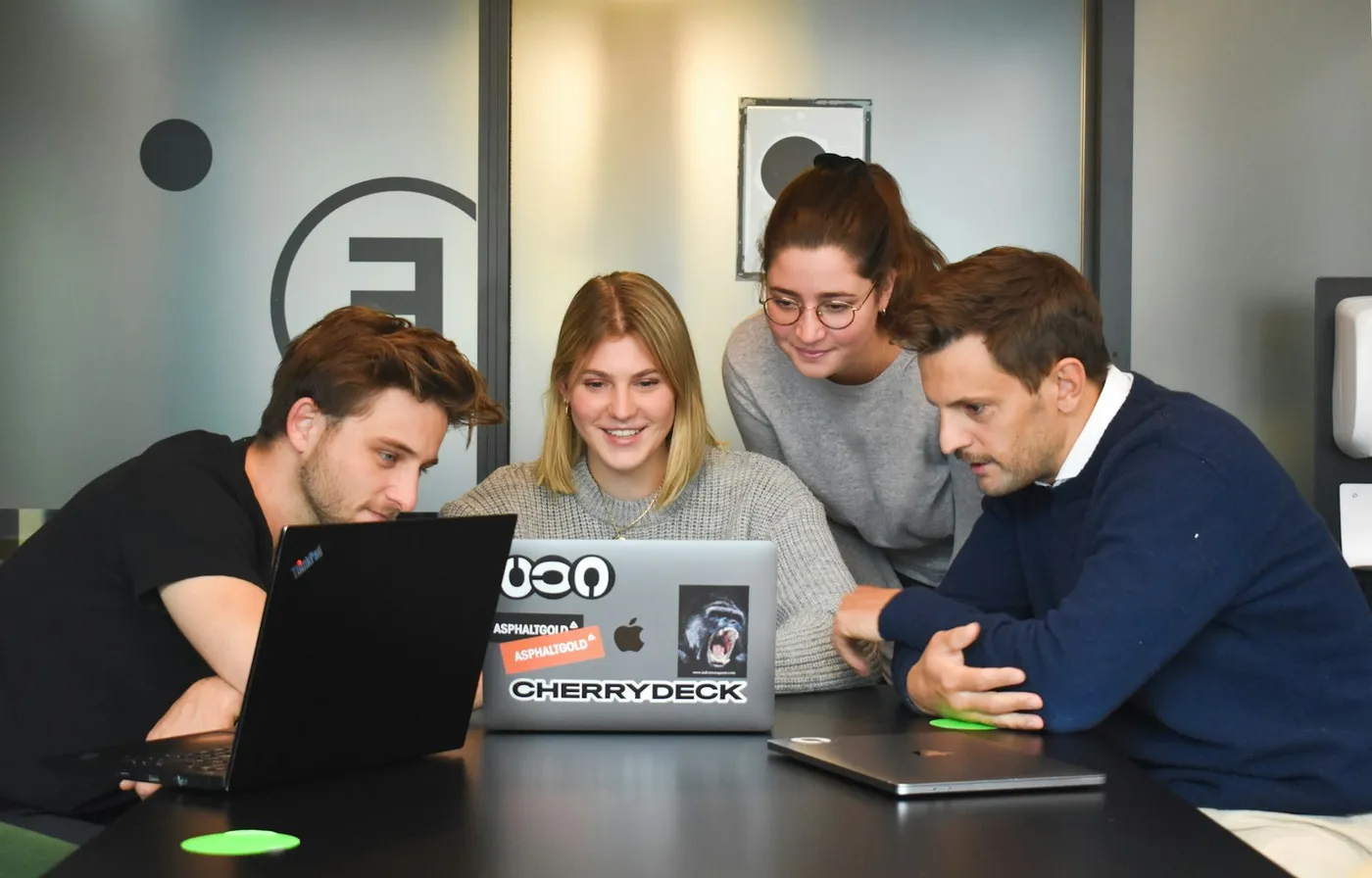 Agency team gathered around a laptop reviewing campaign work