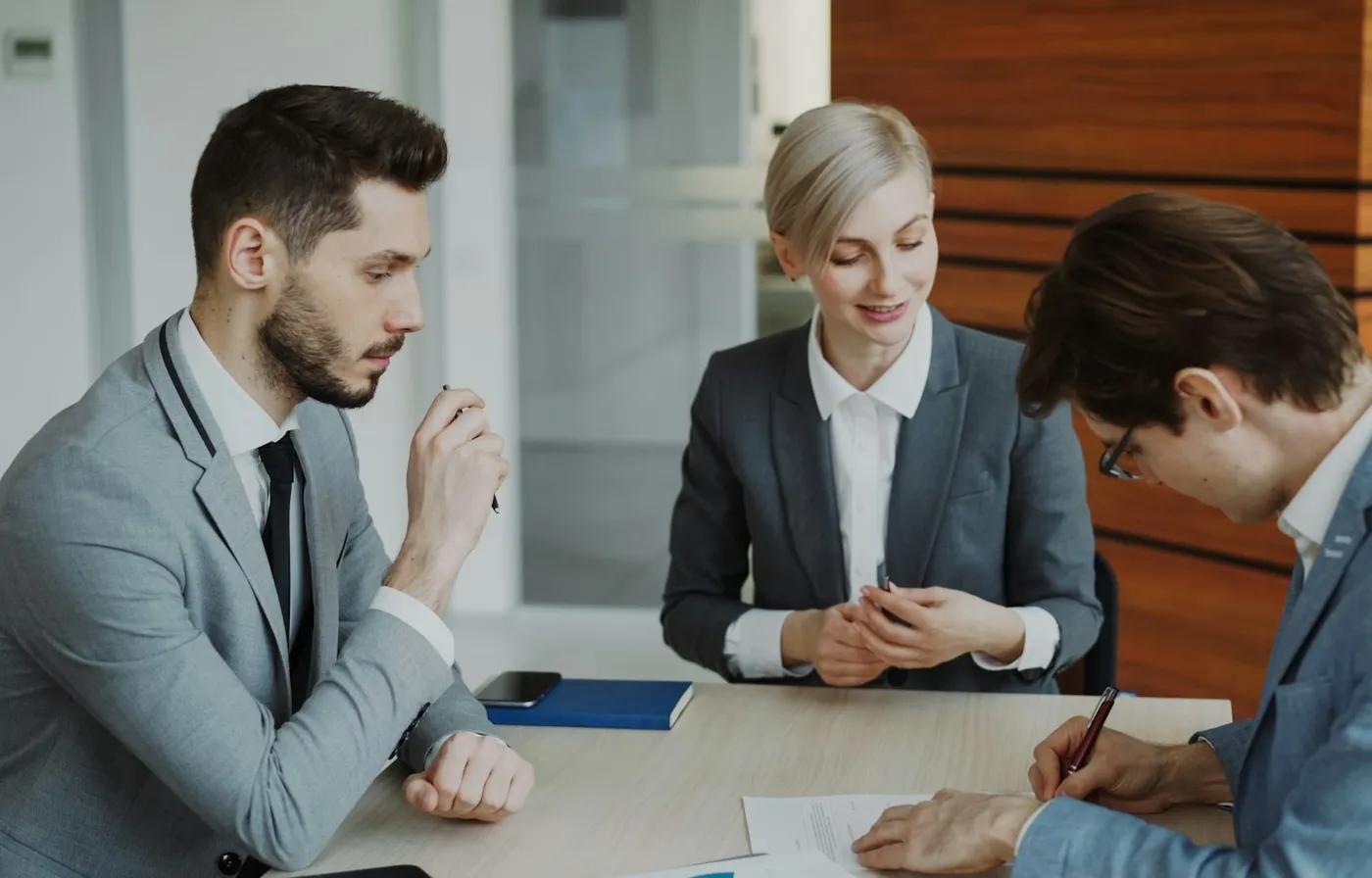 Professionals reviewing and signing a contract at a meeting table